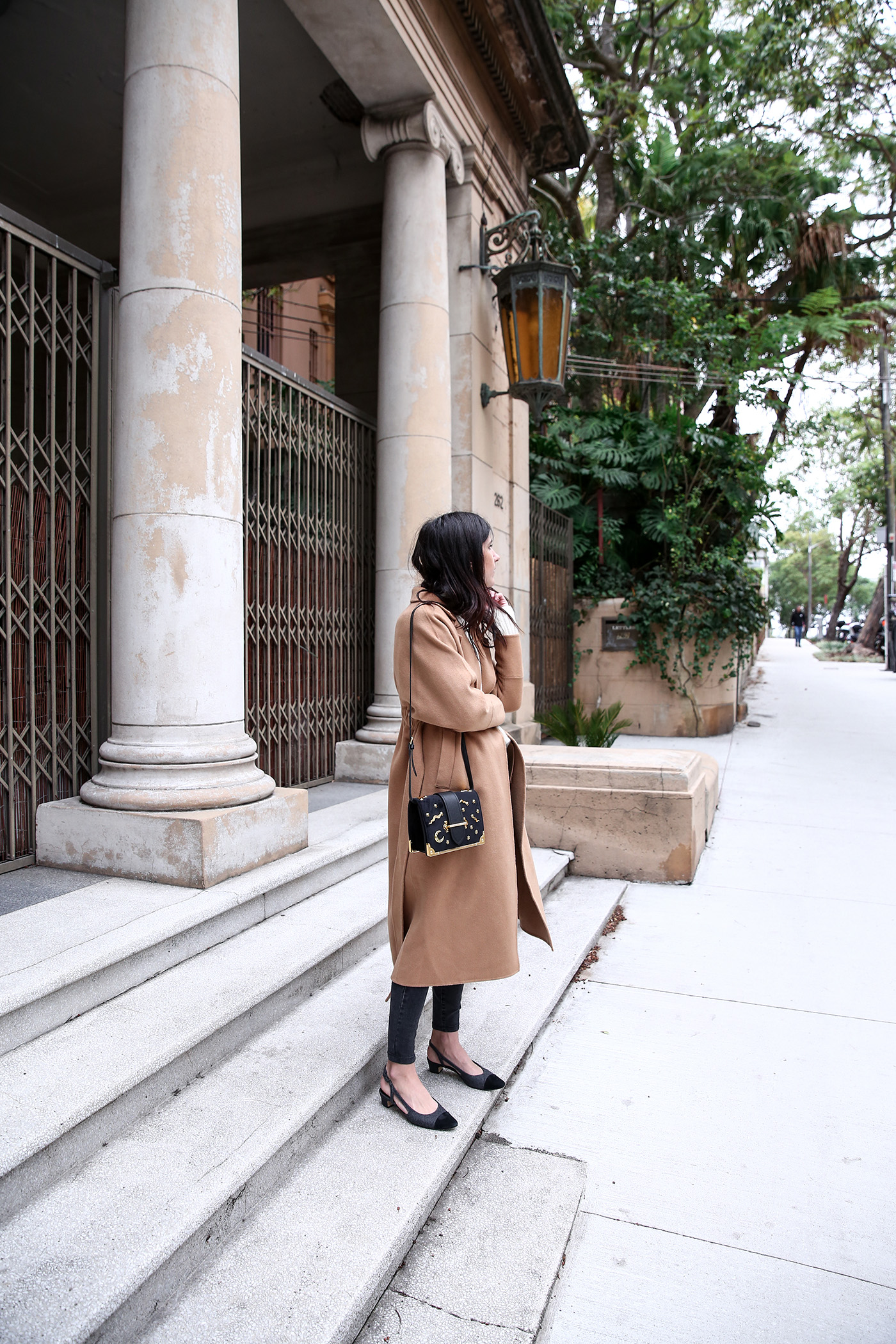 Minimal winter outfit wearing a camel coat with an oversized sweater and skinny jeans