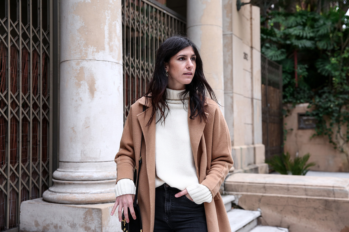 Minimal winter outfit wearing a camel coat with an oversized sweater and skinny jeans