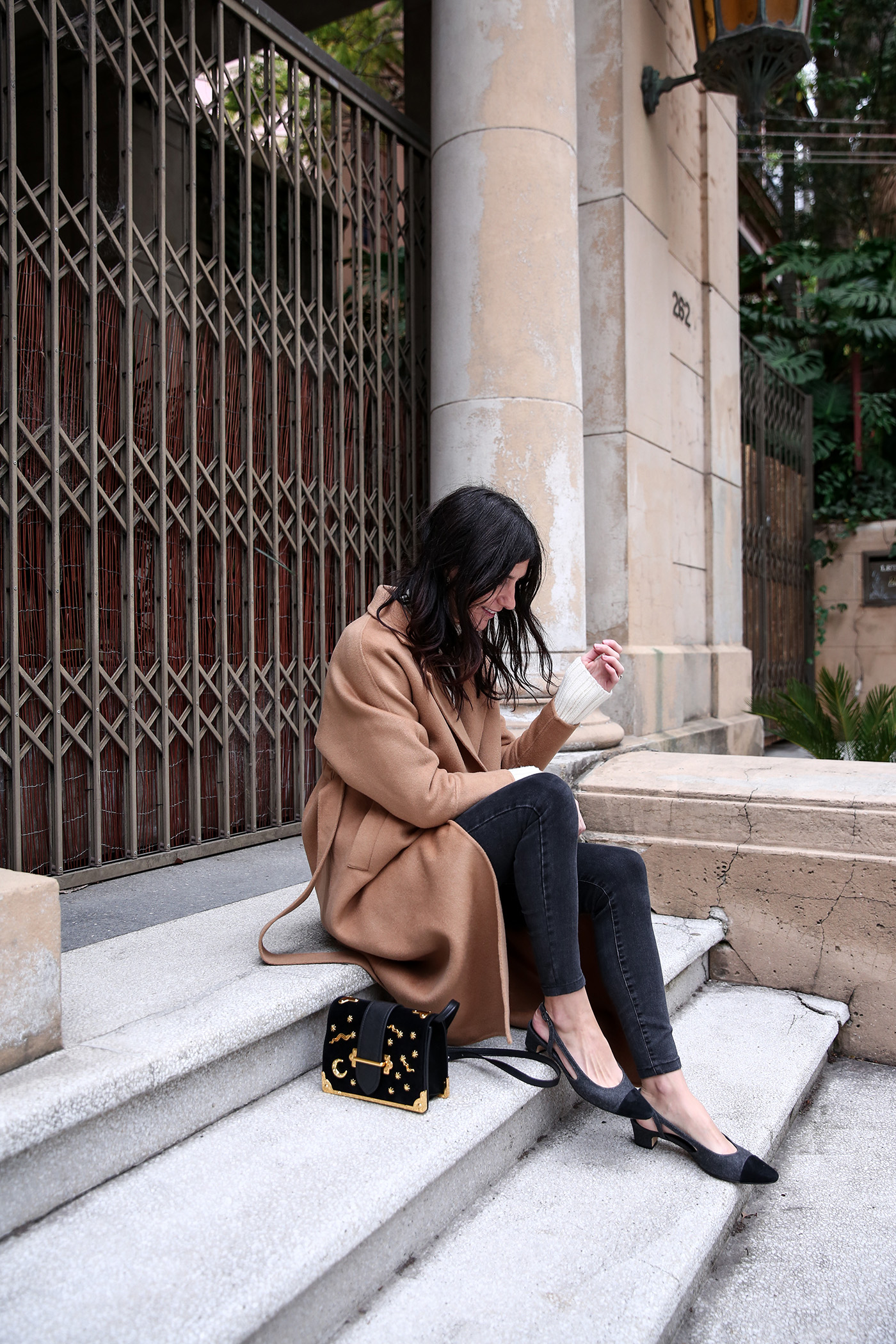 Minimal winter outfit wearing a camel coat with an oversized sweater and skinny jeans