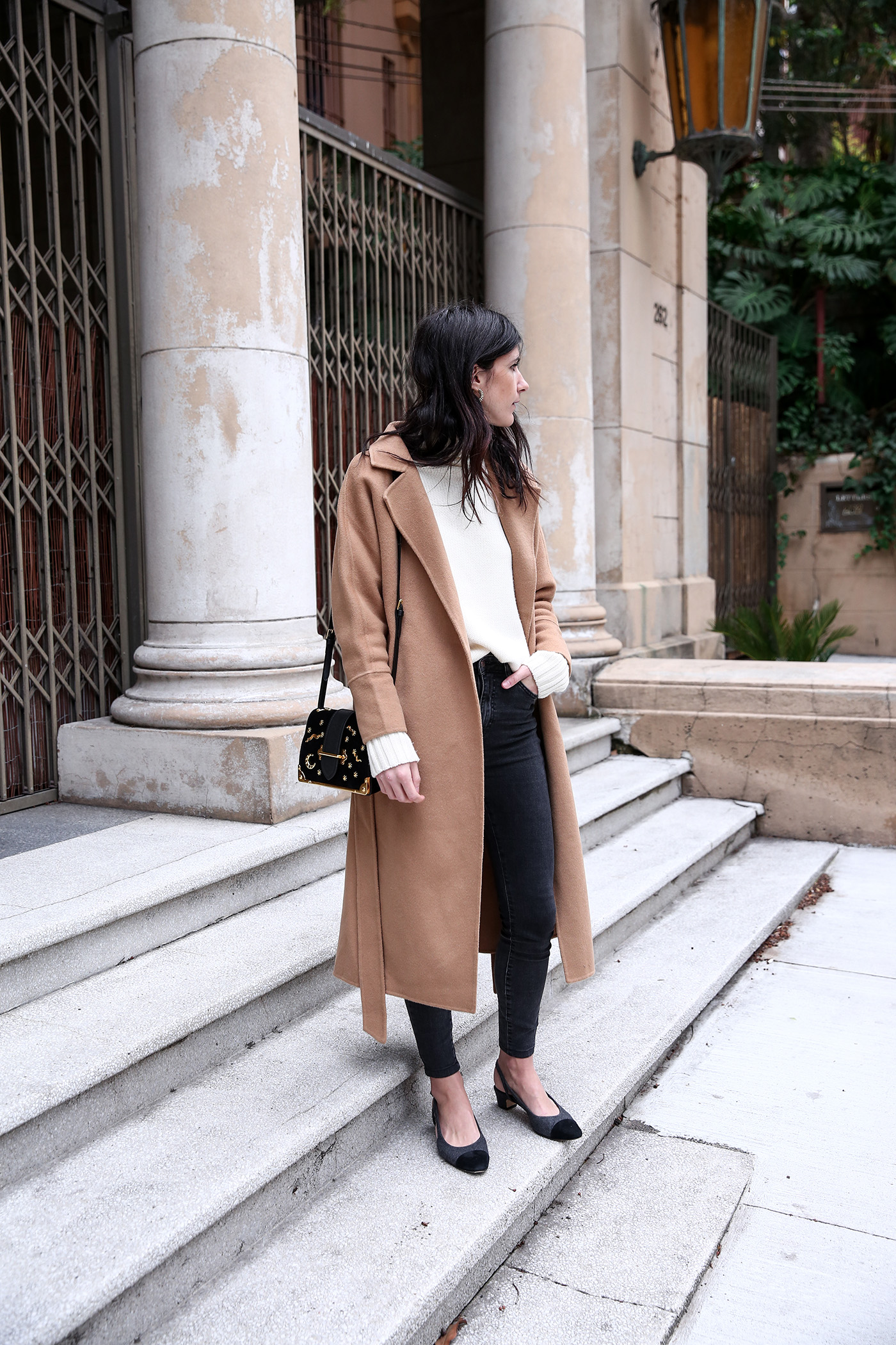 Minimal winter outfit wearing a camel coat with an oversized sweater and skinny jeans