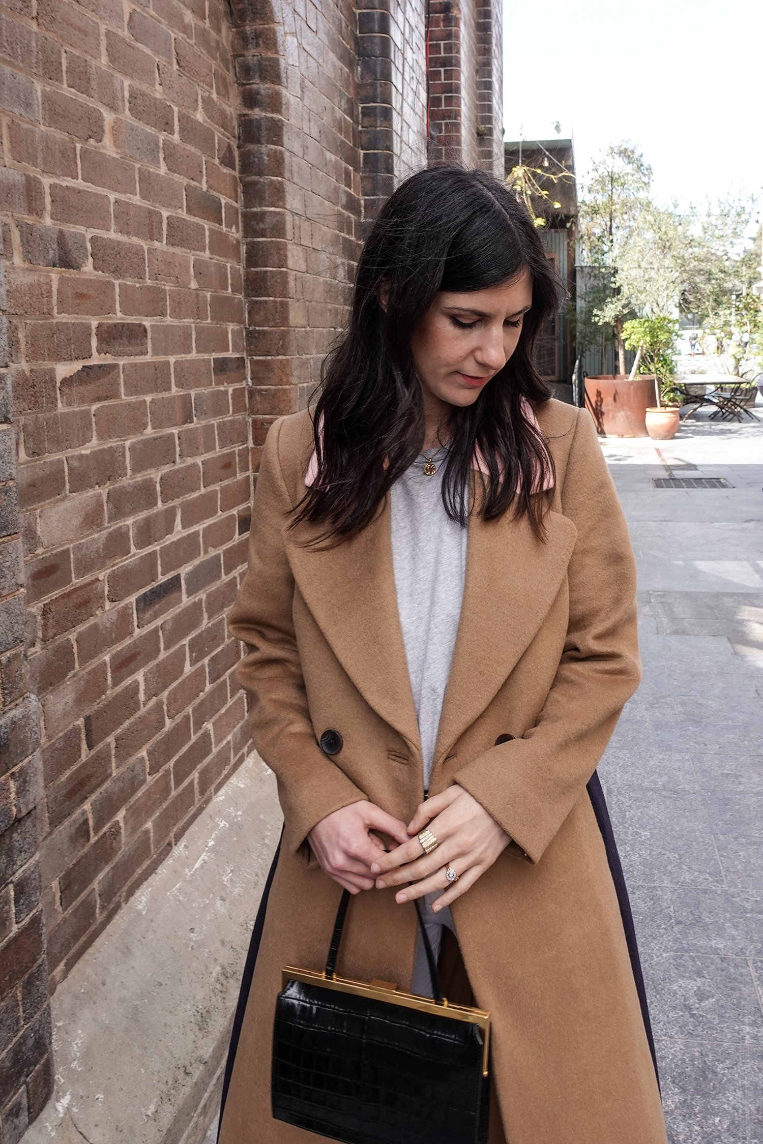 Neutral outfit in a minimal style wearing a camel coat and white jeans