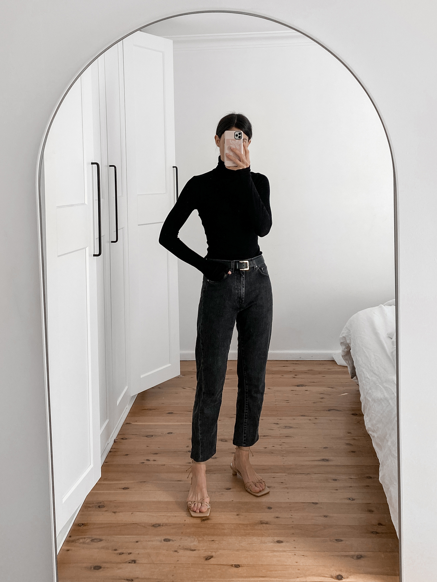 Minimalist all black outfit wearing black roll neck knit and Toteme standard jeans