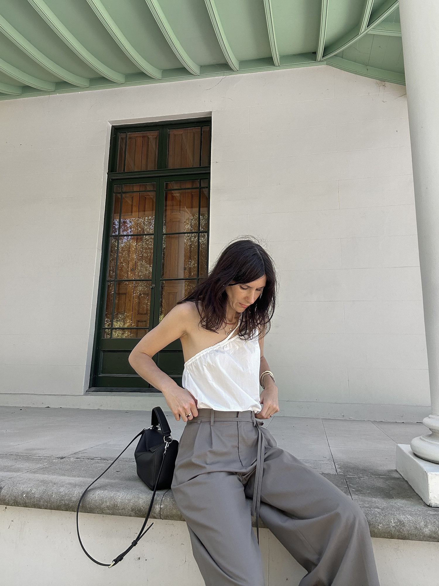 Minimal style wearing one shoulder tank and taupe trousers